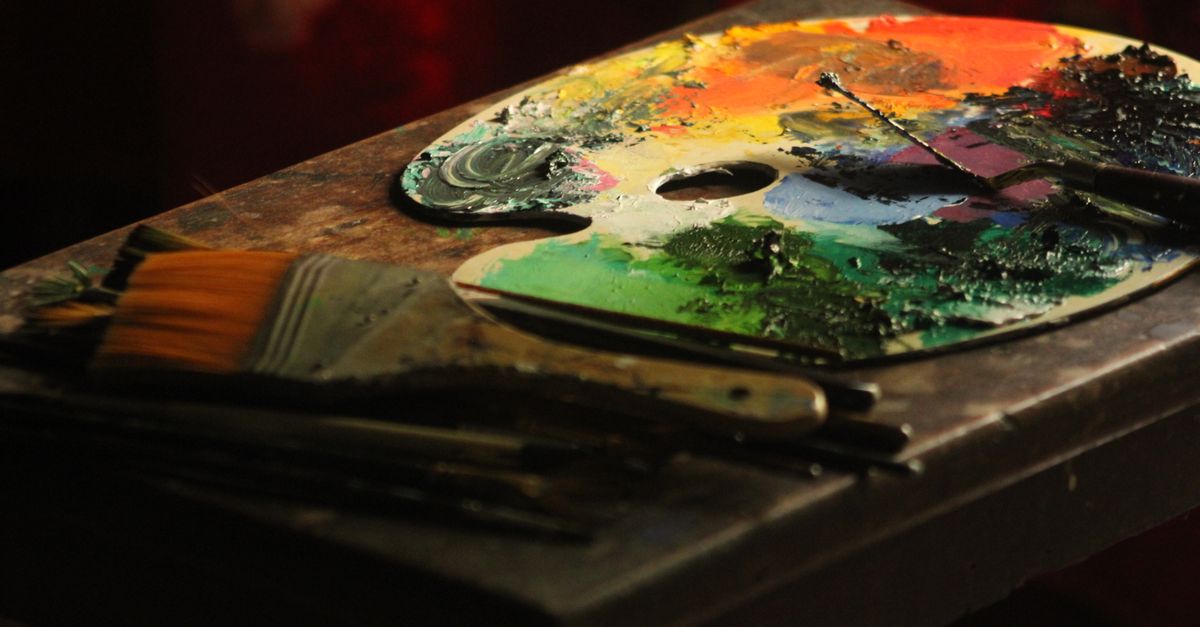 Colorful artist palette with paintbrushes on a wooden table, capturing creative energy.